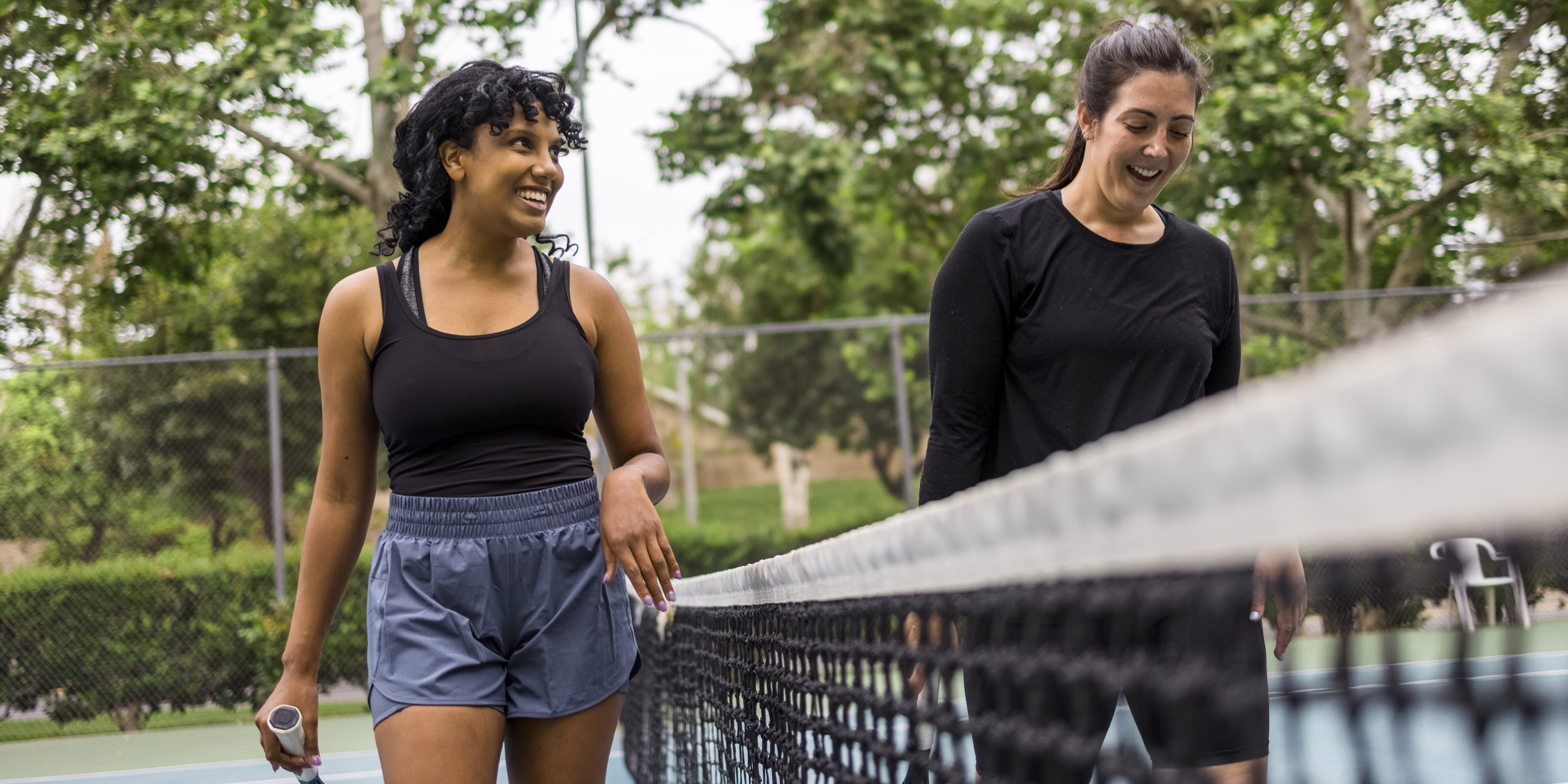 Una joven negra y su madre jugando al tenis.