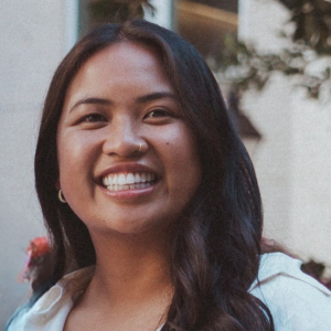 Gaby Elvina smiling at the camera in a white top