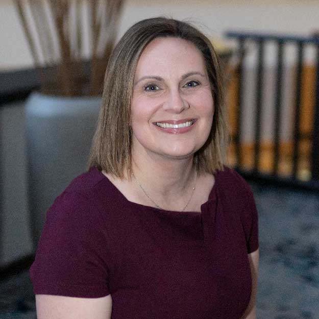 Laura McLoughlin smiling indoors in a professional setting.