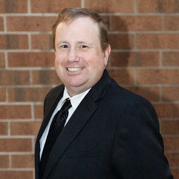 Tyson Thompson smiles in front of a brick background.