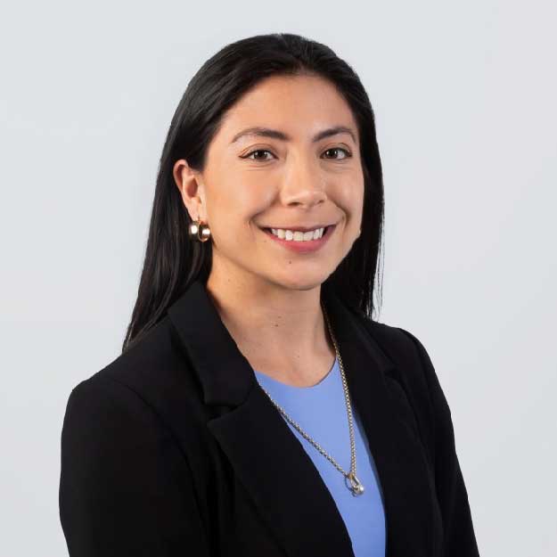 Miranda Rodriguez smiles in front of a plain gray background.