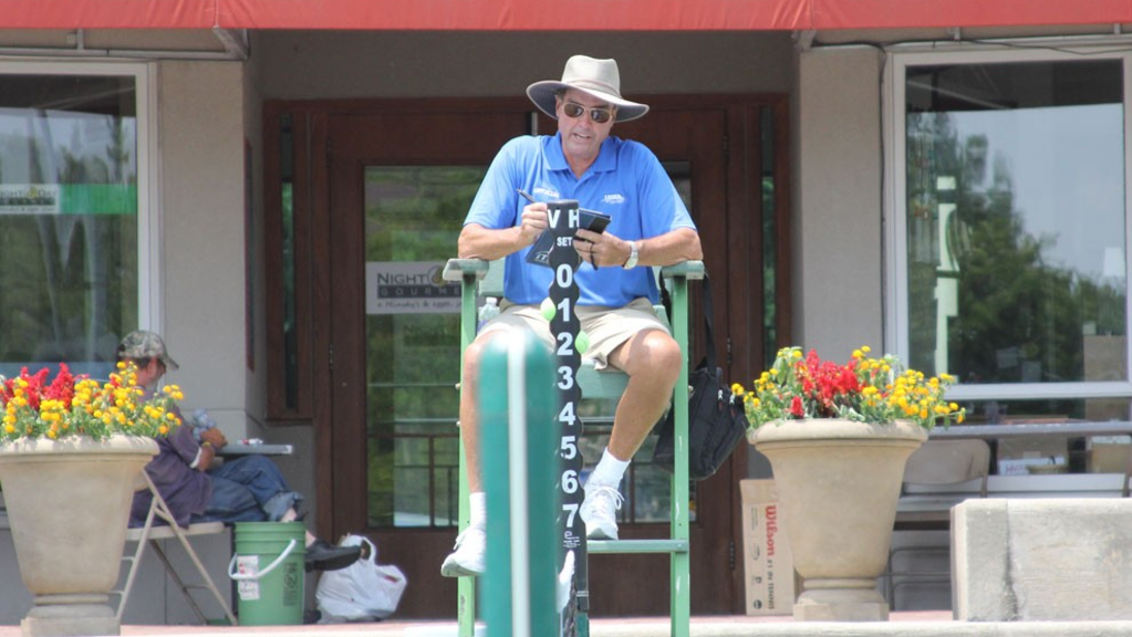 A tennis official writing something down on a notepad.