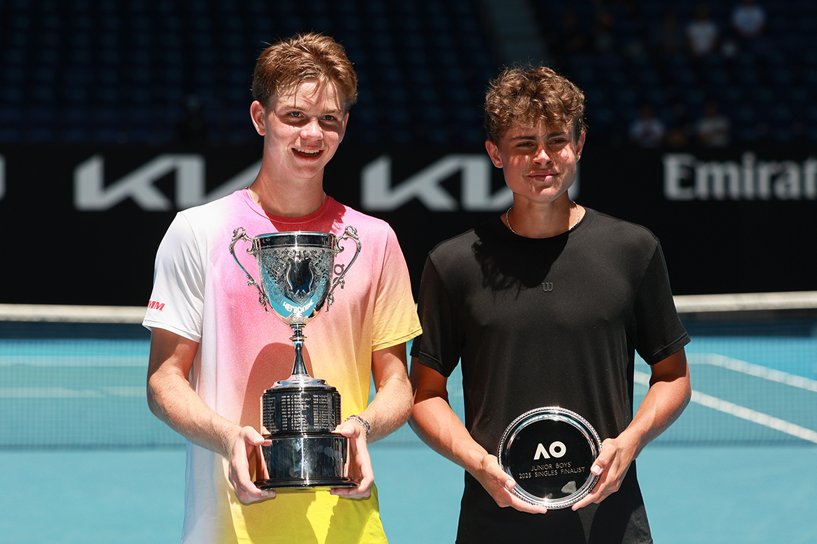 Dos niños están uno al lado del otro sosteniendo trofeos.